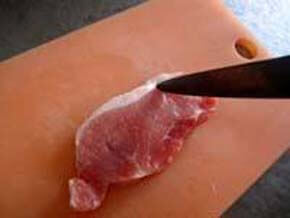 豚ロース肉はそらないよう、包丁で筋切りをする